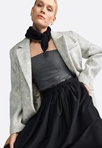 Sacou din amestec de lână de culoare gri deschis peste un top strapless gri închis și o fustă neagră cu talie înaltă, cu un brâu plisat; accesoriu eșarfă neagră.