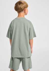 Ljusgrön bomulls T-shirt med kort ärm, avslappnad passform och rundad halsringning, tillsammans med matchande shorts. Mjuk textur, enkelt mönster.