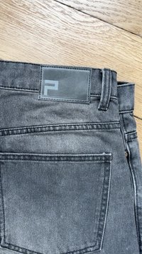Sivi denim hlače z teksturiranim zaključkom, s pravokotno usnjeno nalepko na pasu, ki vsebuje subtilno logotip in dve zadnji žep.