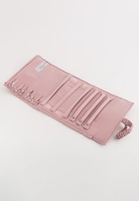 Rosa tyg rullbar organiser med flera elastiska remmar och tryckknappar. Slät textur, med en rynkad handtag i ena änden.