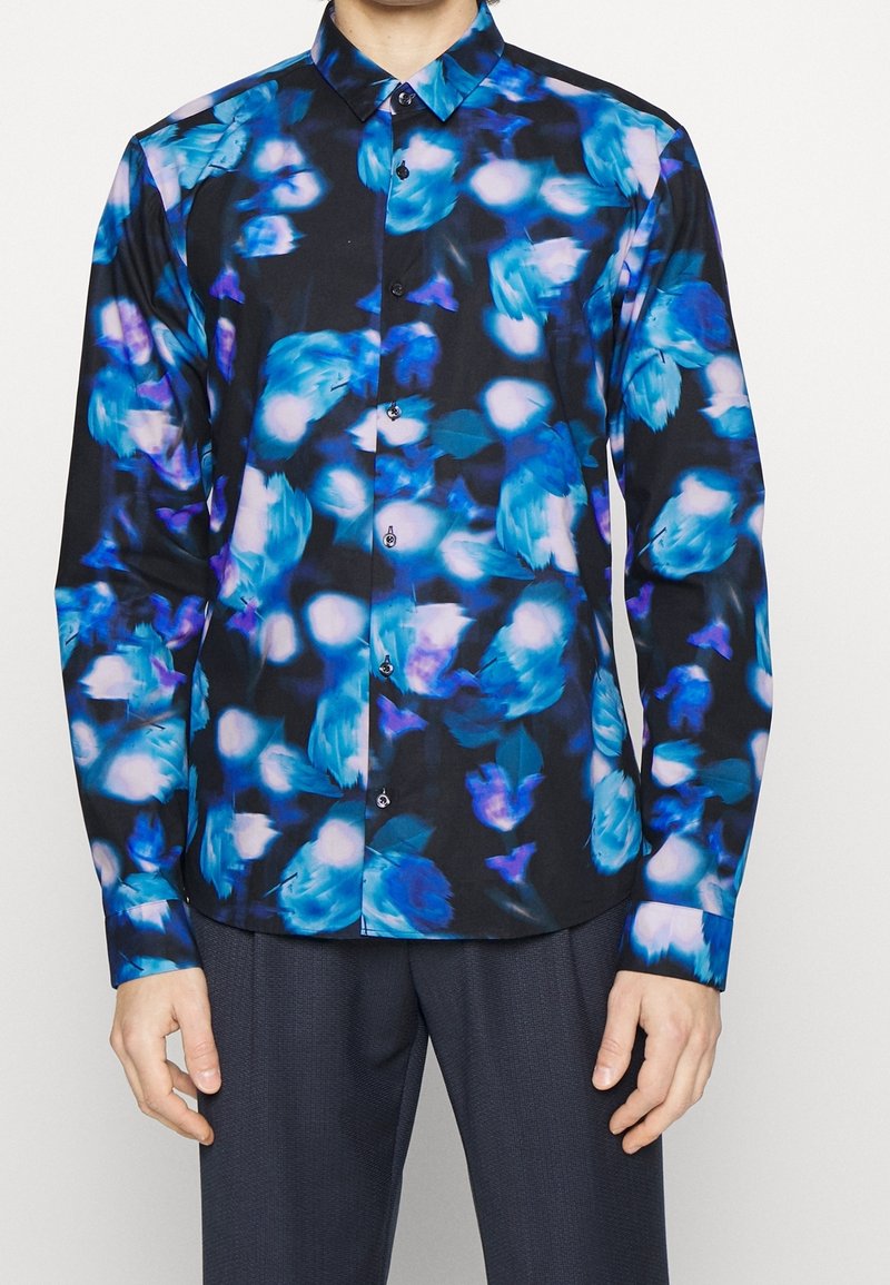 Camisa de manga larga en negro con un vibrante patrón floral en azul, que presenta un cuello clásico y botones en la parte delantera, fabricada en una tela suave.