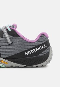 Zapatilla de malla gris con acentos púrpuras, presenta un diseño de cordones, marca Merrell y una suela Vibram para mayor tracción.