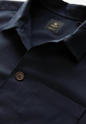 Marineblaues kurzärmliges Hemd aus glattem Stoff, mit Knopfverschluss, Brusttasche und einem Kragen mit Steppdetails.