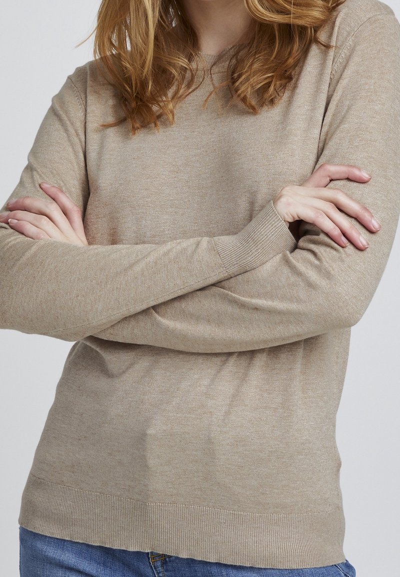Beige Strickpullover mit langen Ärmeln, gerippten Bündchen und Saum. Weicher Stoff, leicht taillierte Passform und dezentes gesprenkeltes Muster.