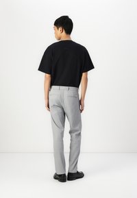 Camiseta negra de manga corta, pantalones ajustados gris claro y zapatos negros. Textura de tela suave, diseño simple y paleta de colores neutros.