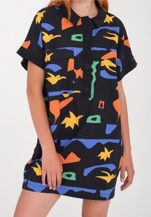 Robe noire à manches courtes avec col et boutons, ornée de formes abstraites colorées en jaune, bleu, orange et vert, portée par une personne.