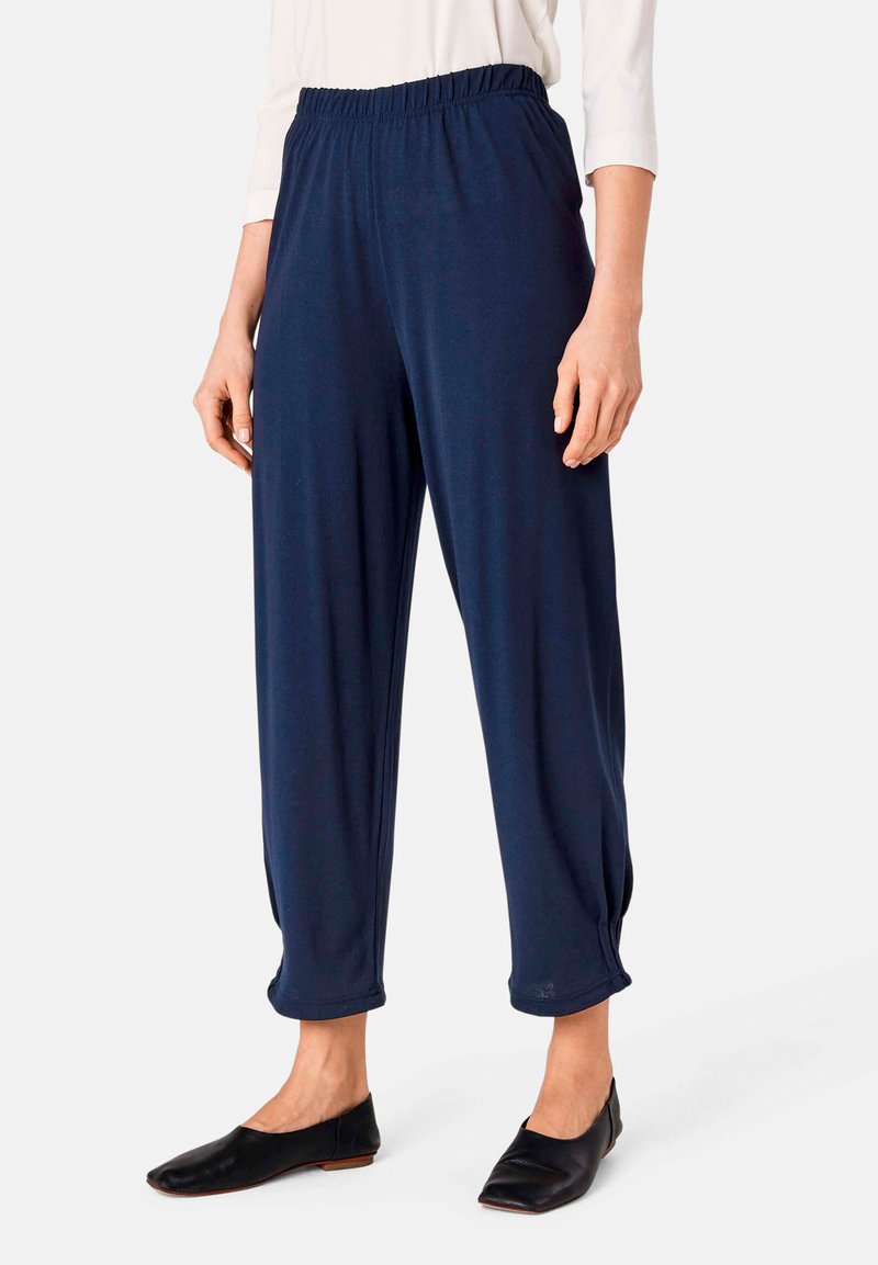 Marineblaue, leichte Hosen mit elastischem Bund, taillierter Beinform und Raffung an den Knöcheln. Weiche, glatte Textur.