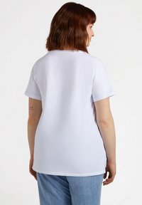 T-shirt bianco a maniche corte realizzato in tessuto morbido, con vestibilità comoda, scollatura rotonda e orli delle maniche arrotolati.