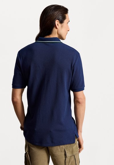 Granatowa koszulka polo z krótkim rękawem, klasycznym kołnierzykiem i zielonymi akcentami, wykonana z teksturowanej bawełny.