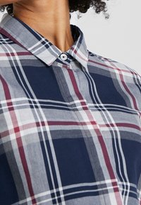 Kariertes Hemd in Marineblau aus Baumwolle. Verfügt über einen Button-Down-Kragen, weiße und rote Akzente sowie eine glatte Textur.