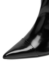 Czarne lakierowane skórzane botki o spiczastym nosie, charakteryzujące się gładkim, połyskującym wykończeniem oraz minimalistycznym stylem, z subtelnym detalem szwu w okolicy kostki.