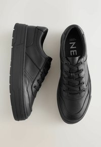 Czarne sneakersy z teksturowaną skórzaną cholewką, sznurowanym zapięciem, wyściełanym kołnierzem oraz masywną gumową podeszwą, z delikatnymi detalami szwy.