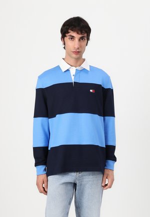 Long-sleeve polo shirt in light and dark blue stripes with a white collar. Features a small logo on the chest. Cotton material.