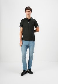 Must mustre shirt valge äärega, kombineeritud helesiniste teksade ja mustade tossudega. Kitsas lõige, lühikesed varrukad, kolme nupuga kaelus, lihtne disain.