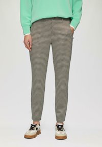 Lekka, wzorzysta para spodni w zielono-beżowym kolorze, o dopasowanym kroju, elastycznej talii, bocznych kieszeniach oraz subtelnym geometrycznym wzorze.