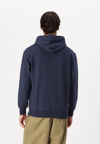 Navy hooded sweatshirt with ribbed cuffs and hem, soft texture, featuring a kangaroo pocket and a simple, minimalistic design.