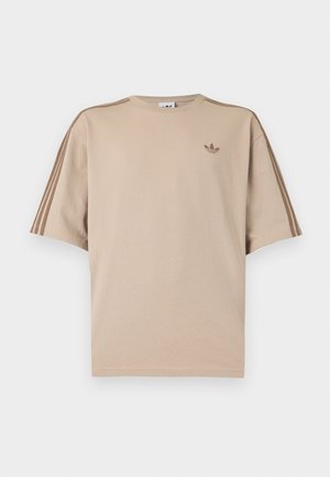 Beżowy t-shirt z krótkim rękawem i okrągłym dekoltem, z trzema ciemniejszymi beżowymi paskami na każdym rękawie oraz małym logo Adidas na lewym piersi.