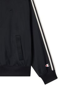 Giacca sportiva nera con strisce laterali bianche, polsini e orlo a coste, texture intrecciata, caratterizzata da un piccolo logo sulla manica e sul davanti.