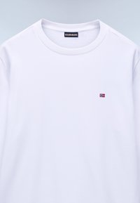 Λευκό μακρυμάνικο μπλουζάκι από μαλακό ύφασμα με στρογγυλή λαιμόκοψη. Διαθέτει μικρή κεντημένη σημαία της Νορβηγίας στο αριστερό μέρος του στήθους.