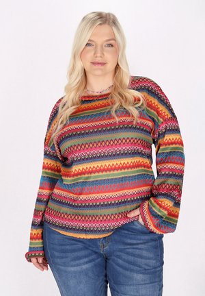 Flerfarvet sweater med livlige zigzag- og geometriske mønstre, lavet af et tekstureret strikket stof med lange ærmer. Kombineret med jeans.