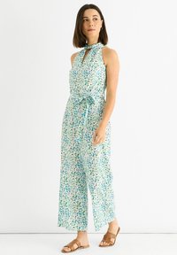Floral jumpsuit featuring a halter neck, cut-out keyhole detail, and a belted waist in shades of blue and green on a light background.