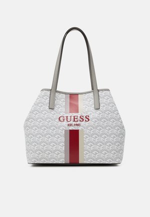 Hvid Guess tote taske med gråt mønster, lodrette røde og beige striber, rød logo tekst og dobbelte grå håndtag.