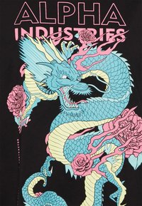 Must have t-särk musta värviga, millel on türkiissinine draakonigraafika, mis on põimunud roosade roosidega ja leekidega, peal roosa tekst "ALPHA INDUSTRIES".