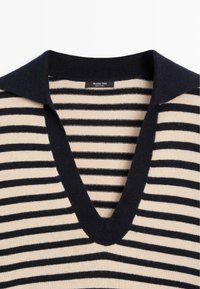 Maglione a righe con colori navy e beige, caratterizzato da scollo a V e colletto a contrasto. Tessuto morbido a maglia con motivo a righe uniforme.