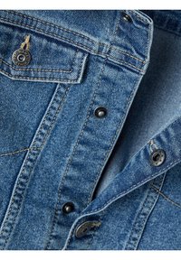 Džínová košile v světle modré barvě, výrazné švy, černé knoflíky a náprsní kapsa s logovou nášivkou.