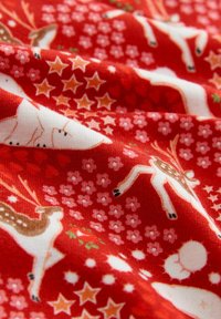 Červená látka s bielymi sobmi, béžovými hviezdami, malými ružovými kvetmi a bielymi snehuliakmi v sviatočnom vianočnom vzore.