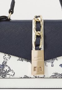 Sac à main bleu marine avec un corps texturé, un détail en chaîne dorée et un imprimé floral blanc. Dispose d'un fermoir rectangulaire et d'une bandoulière réglable.