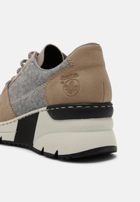 Sneaker marrone e grigia con tomaia in suede, pannello laterale in feltro, suola testurizzata bianca e nera e logo in rilievo sul tallone.