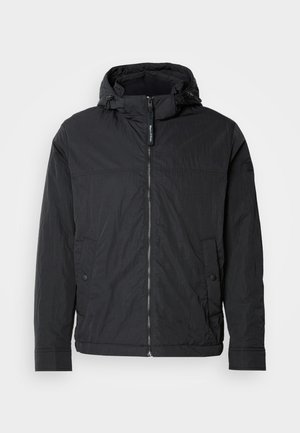 Črna jakna s kapuco iz lahkega, teksturiranega blaga. Na sprednji strani ima zadrgo, dva žepa in elastične manšete. Enostaven dizajn.