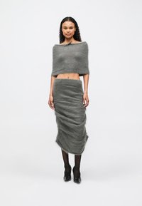 Siva pletena kratka majica s širokim izrezom u kombinaciji z ujemajočo tesno krilno krilo; oba kosa imata mehak, puhast videz.