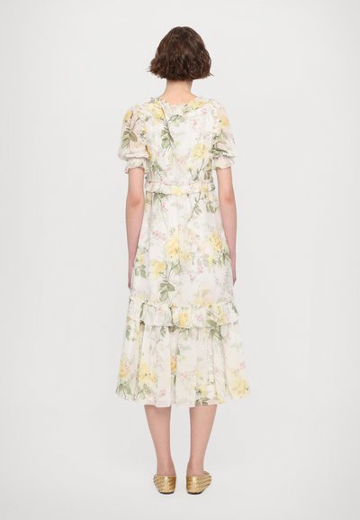 Bloemige midi-jurk met pofmouwen, ruches en een getailleerde taille. Kleuren zijn zachte gele, groene en roze tinten op een lichte achtergrond.