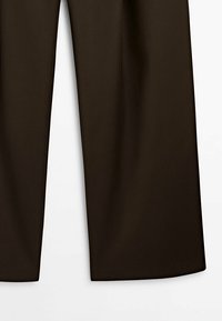 Pantalon large marron foncé présenté de la mi-cuisse à l’ourlet sur un fond uni clair.