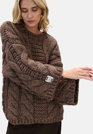 Brązowy, oversize'owy sweter dziany z warkoczowymi wzorami, teksturowaną tkaniną, szerokimi rękawami i metką przyszytą na dole.