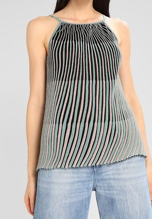 Femme portant un haut sans manches en maille plissée avec des rayures verticales noires, grises et rose clair, assorti à un jean bleu clair.