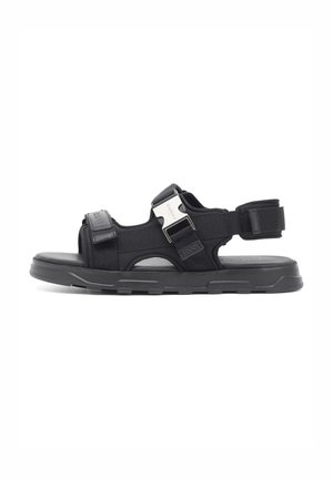 Schwarze Sandale aus Stoff und synthetischen Materialien, mit verstellbarem Riemen, strukturiertem Fußbett und robuster Gummisohle.