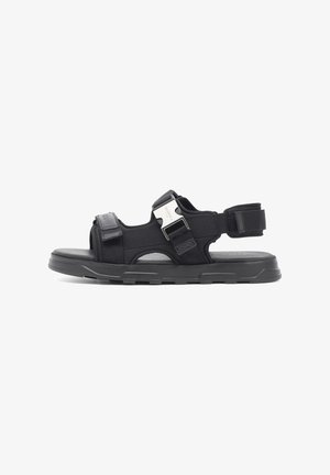 Sandal nero realizzato in tessuto e materiali sintetici, con cinturino regolabile, soletta testurizzata e suola in gomma chunky.