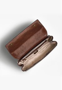 Pochette in kraft marrone, con texture, aperta per mostrare l'interno in tessuto beige con scomparto con zip e fodera con logo Guess.
