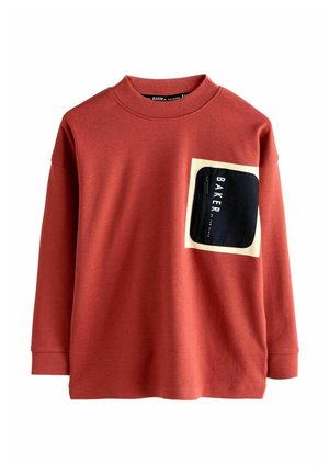 Maglietta rossa a maniche lunghe in cotone, con tasca con zip nera e testo "BAKER" su sfondo crema. Collo a giro classico.