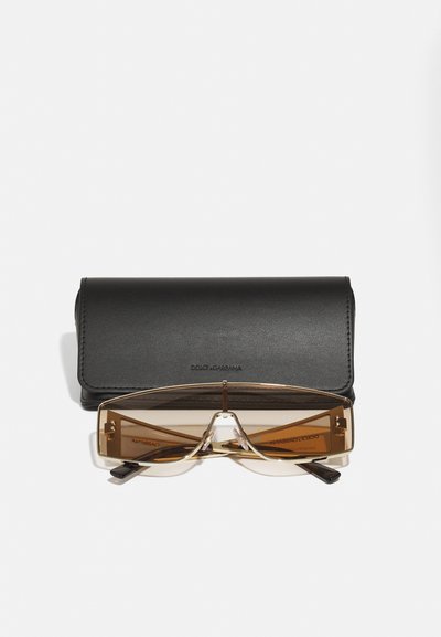 Ochelari de soare dreptunghiulari, maro, cu ramă transparentă, expuși deasupra unei cutii din piele neagră. Cutița are o textură netedă și un logo embosat.