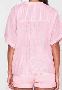 Růžový pruhovaný top s krátkými rukávy, detailem skladů na zadní straně a volným střihem, doplněný o světle růžové šortky. Texturovaná bavlněná tkanina.