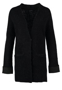 Cardigan nero in materiale felpato con apertura frontale, maniche lunghe e due tasche anteriori. Presenta un polsino grigio scuro a contrasto.