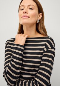 Haut à rayures noir et beige à manches longues avec un col bateau. Tissu doux avec une coupe décontractée et un minimum de couture au niveau des poignets.
