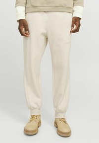 Beige sweatpants med ribbet ankler, lavet af blødt materiale. Diskret logo detalje på fronten. Sammen med letvægtige beige sko.