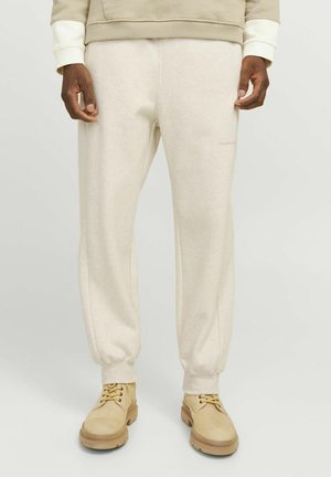 Beige sweatpants med ribbet ankler, lavet af blødt materiale. Diskret logo detalje på fronten. Sammen med letvægtige beige sko.