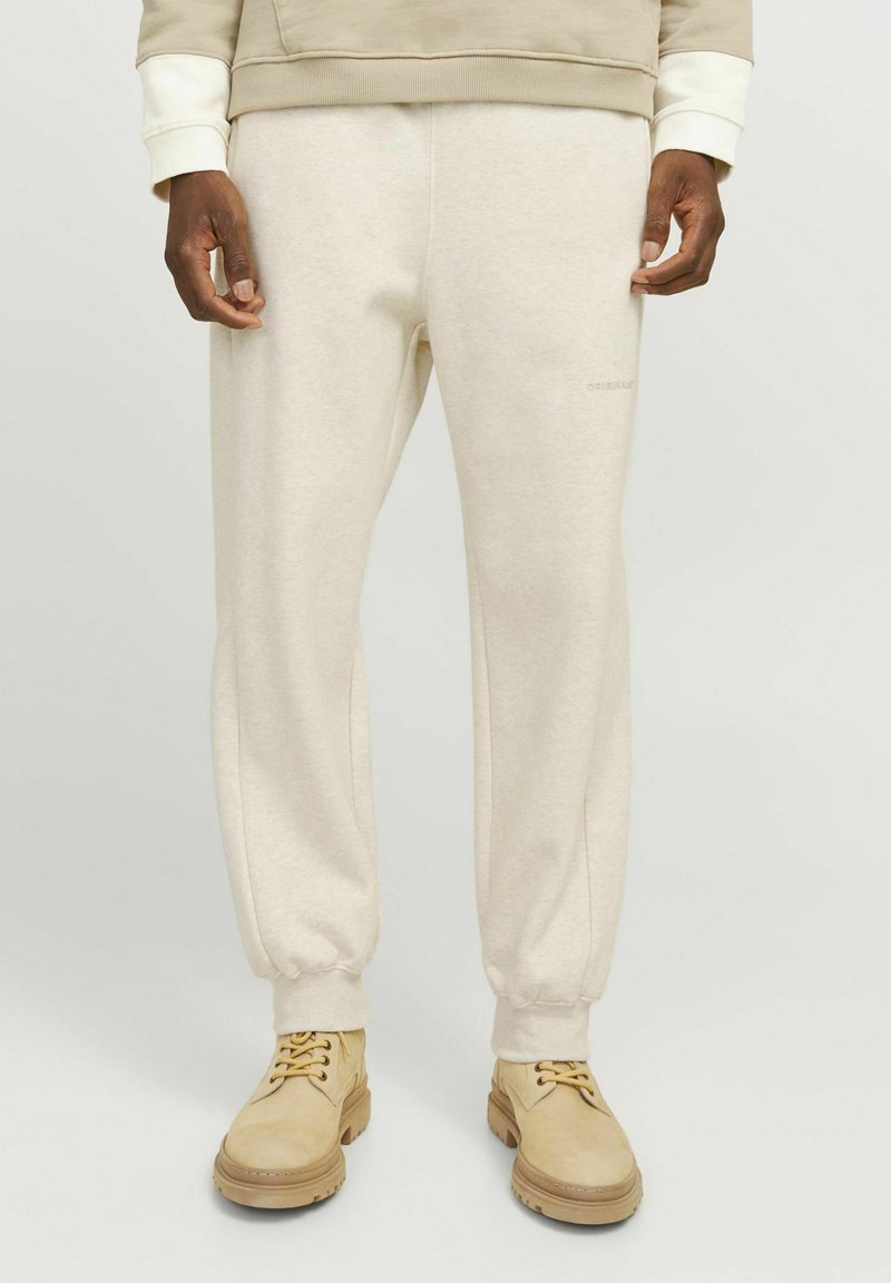 Beige sweatpants med ribbet ankler, lavet af blødt materiale. Diskret logo detalje på fronten. Sammen med letvægtige beige sko.