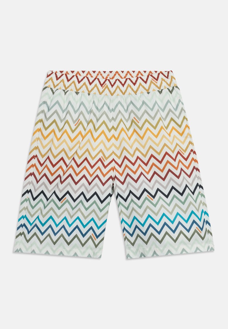 Shorts courts avec motif zigzag multicolore en rouge, jaune, bleu et vert sur fond blanc, taille élastique avec motif zigzag.
